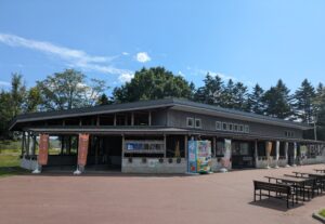 道の駅阿寒丹頂の里「クレインズテラス」の外観。木造のあたたかみある建物と自動販売機、ベンチが並ぶ様子。
